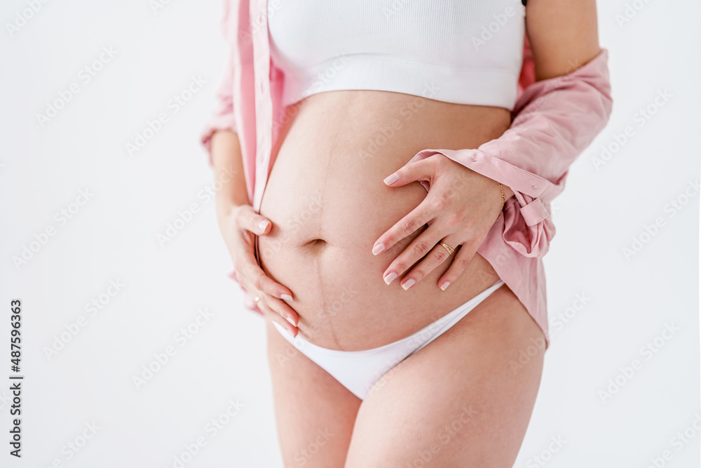 custom made wallpaper toronto digitalA pregnant woman in a pink shirt touches her big belly on a white background. The concept of motherhood, pregnancy and baby waiting. Copy space, banner