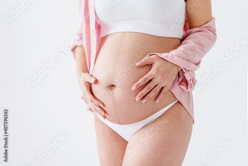 Wallpaper Mural A pregnant woman in a pink shirt touches her big belly on a white background. The concept of motherhood, pregnancy and baby waiting. Copy space, banner Torontodigital.ca