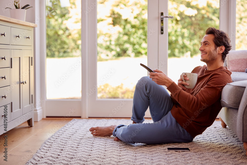 Man At Home Sitting On Floor With Remote Control Watching TV Man At Home Sitting On Floor With Remote Control Watching TV
