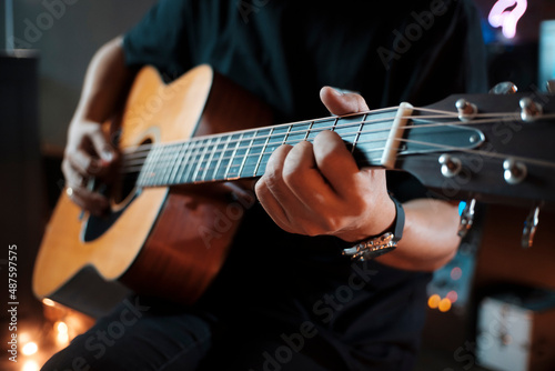 man's hands playing acoustic guitar.