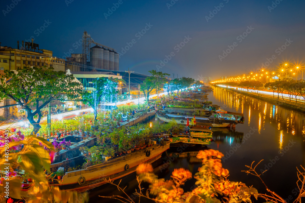 Fototapeta premium Springtime in Saigon, boat on canal, transport spring flower for Tet to Ben Binh Dong open air market, Vietnamese happy with Lunar New Year, Vietnam