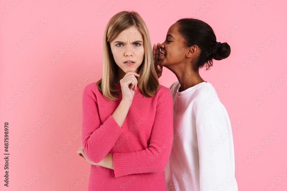 Black girl smiling while whispering secret to displeased friend Black girl smiling while whispering secret to displeased friend