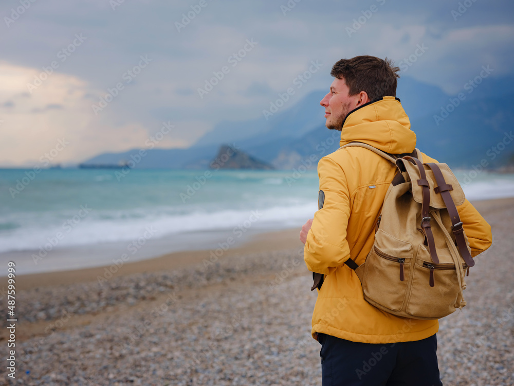 Handsome man in yellow jacket walking beach in antalya, turkey. Good looking male model looking pensive at ocean sea. Fantasy storytelling content Handsome man in yellow jacket walking beach in antalya, turkey. Good looking male model looking pensive at ocean sea. Fantasy storytelling content