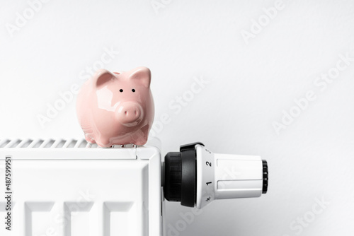 Sparschwein steht auf Heizkörper mit Thermostat