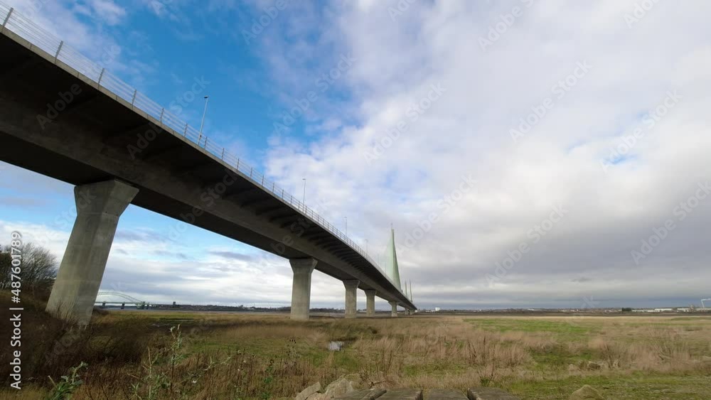 Speeding time lapse clouds passing over suspension bridge on rural countryside marshland development Speeding time lapse clouds passing over suspension bridge on rural countryside marshland development