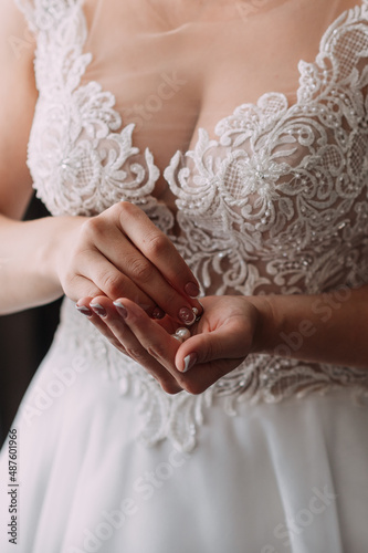 The bride in an openwork dress holds a necklace in her hands 3794.