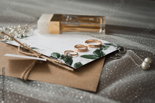 Wedding jewelry, perfumes and envelopes with invitations on the table