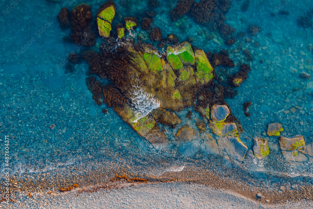 Fototapeta premium Aerial view of transparent sea with stones and coastline