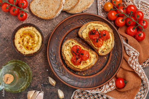 Healthy vegetarian sandwiches with whole grain bread, hummus, baked tomatoes and spices. bruschetta. A delicious snack for gourmets. Rustic style. Selective focus, top view