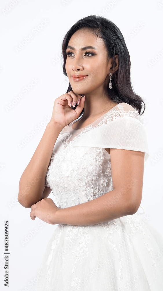 Asian woman in white wedding dress. Thai bride poses before the wedding day. A young woman is happy in a wedding dress. Portrait shot white background in studio. Marriage dress for marriage ceremony. Asian woman in white wedding dress. Thai bride poses before the wedding day. A young woman is happy in a wedding dress. Portrait shot white background in studio. Marriage dress for marriage ceremony.