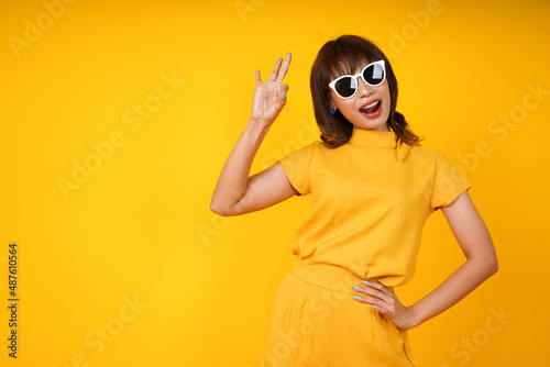 Portrait of smiling young woman okay side copy space isolated on yellow background. people sincere emotions, modern lifestyle advertising area marketing and shopping promotion