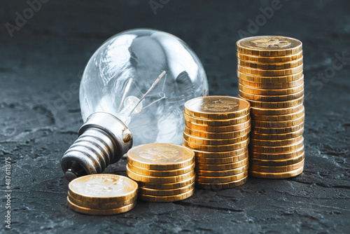 Energy saving.Old lamp. Money coins on a dark background. Energy saving. Stack of coins