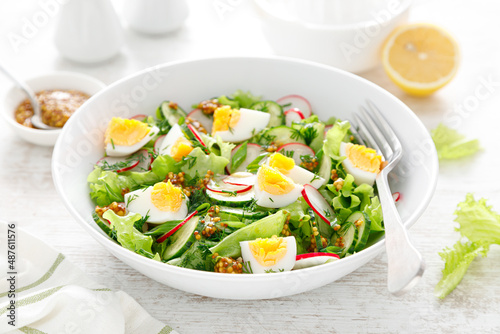 Easter fresh vegetable salad with boiled egg  radish and cucumber  dressing with dijon mustard and lemon on white wooden table