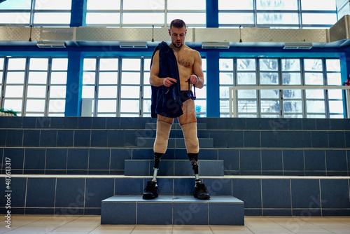 Young adult man with artificial legs standing in the sport center