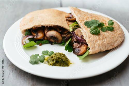 Pita breads filled with sauteed mushrooms and onions with winter purslane and corn salad, served with zhoug