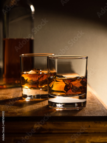 Two glasses of whisky on the rocks on a wooden bartop