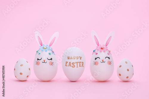 Easter composition of five different eggs on a pink background. White rabbit eggs and decorated golden eggs. Greeting Easter card with copy space.
