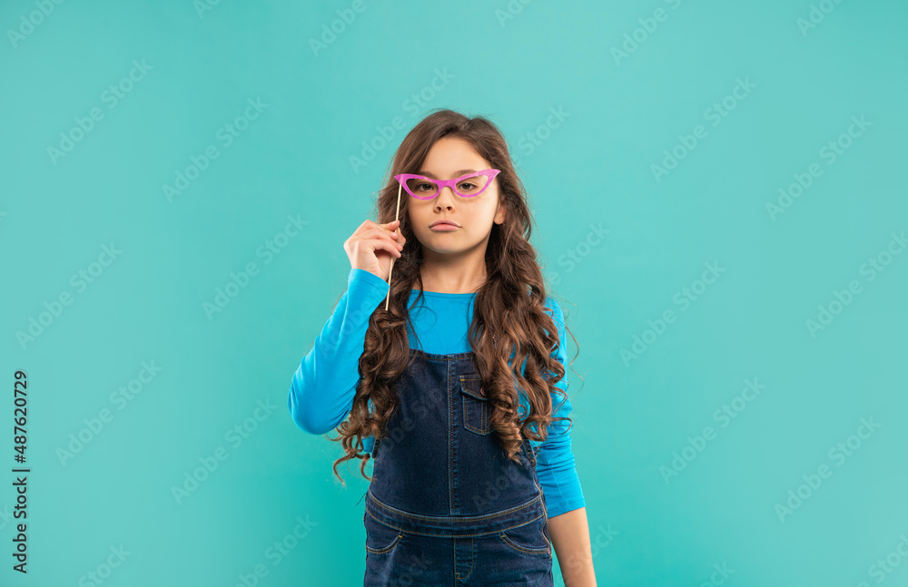 arrogant kid with long curly hair on blue background. funny child with glasses. arrogant kid with long curly hair on blue background. funny child with glasses.
