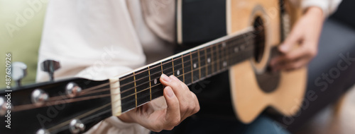 partial view of blurred woman playing guitar at home, banner.