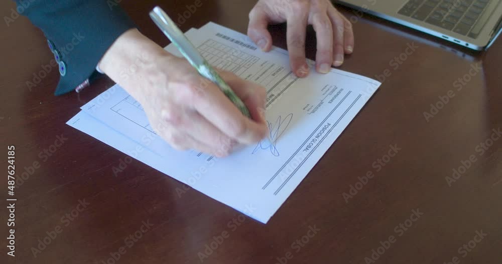 Persona firmando un documento en papel con un bolígrafo
