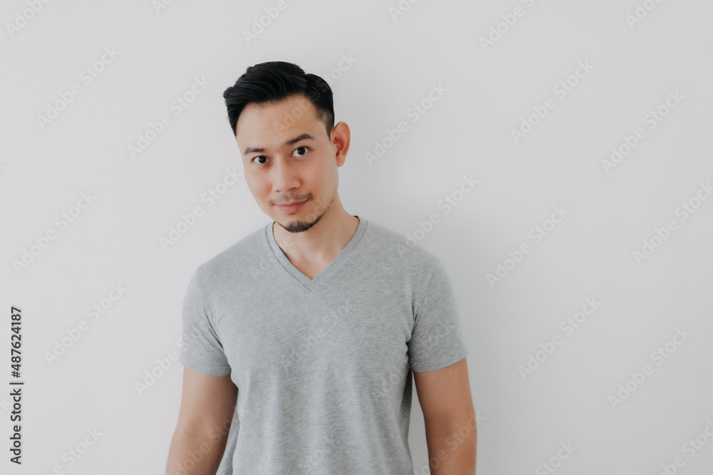 Portrait of Happy Asian man wear grey t-shirt stand isolated on white wall.