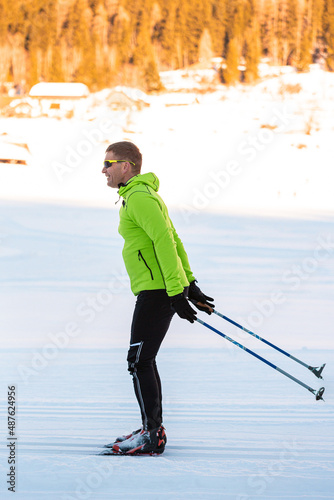 Middle aged man cross country skiing, on the ski trail surrounded by mountains and forest.