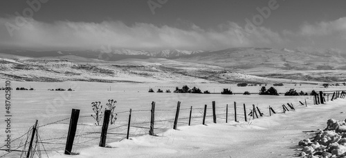 barb wire fence with snowy field and hills