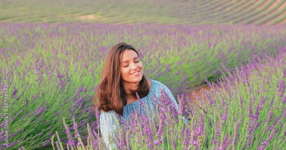 The beautiful young girl walks across the field of a lavender at sunset ...