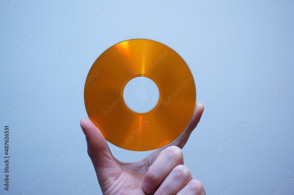 Caucasian hand holding a CD. Orange blank disc. Vintage tech. Caucasian hand holding a CD. Orange blank disc. Vintage tech.