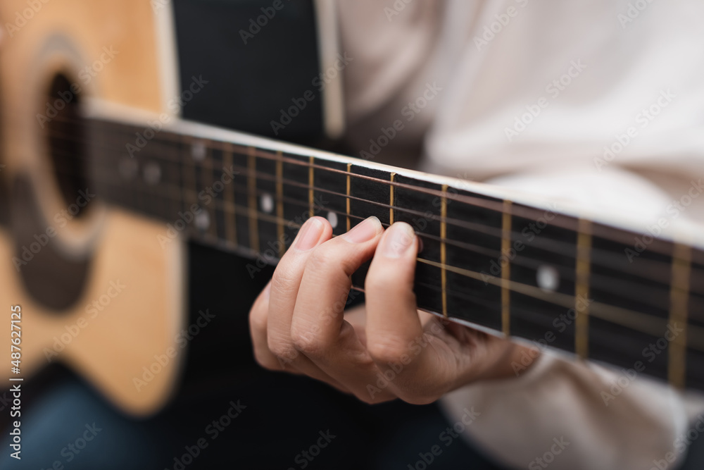 Fototapeta premium partial view of woman playing acoustic guitar, blurred background.