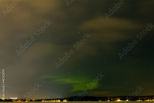 Green Northern Lights on the night sky with stars over snow