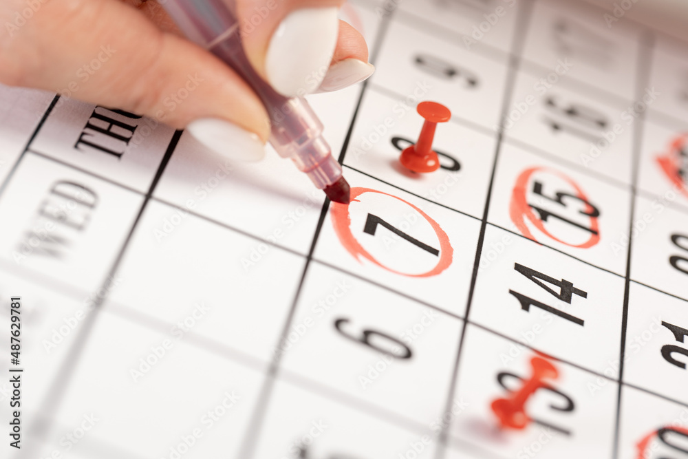 female hand marking with a red pen on a calendar circles the 7 day, deadline concept female hand marking with a red pen on a calendar circles the 7 day, deadline concept
