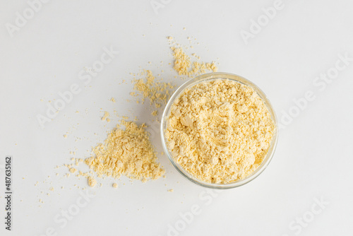 Chickpea flour in glass bowl and scattered on white background, top view photo