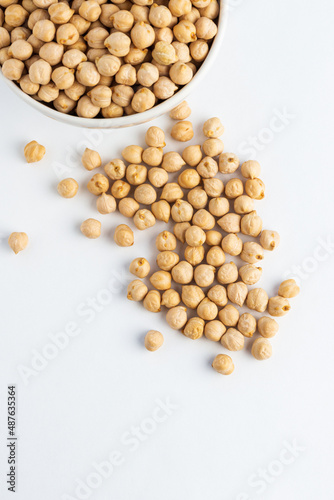 Raw dried chickpea in white plate on white background, top view