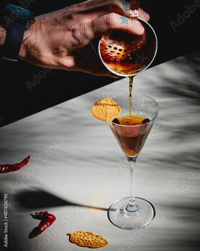spicy martini dark cocktail with a leaf small biscuit and pepper