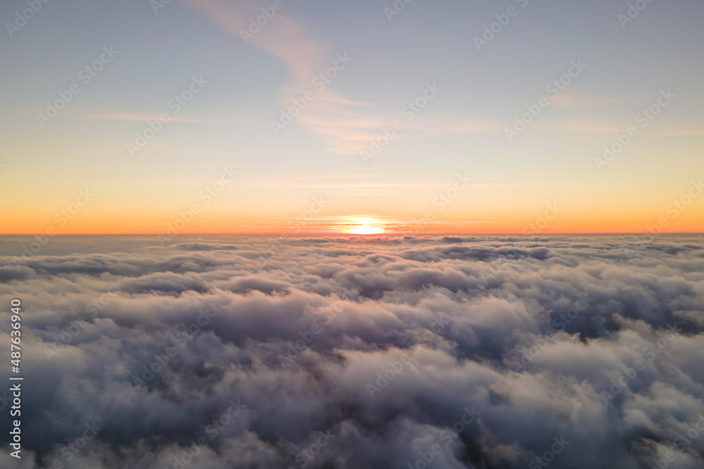 Aerial view from airplane window at high altitude of dense puffy cumulus clouds flying in evening