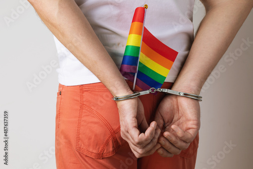 A man in handcuffs with an LGBT flag in his jeans pocket, a concept on the topic of violation of the rights of LGBT minorities and oppression in different countries photo