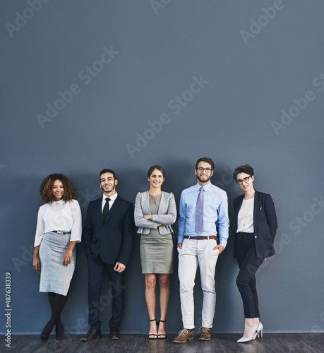 Corporate confidence at its best. Studio shot of a group of businesspeople standing in line against a gray background. photo