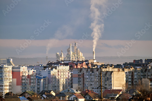 Cement plant with high factory structure and tower cranes at industrial production area near city urban area. Manufacture and global industry concept © bilanol