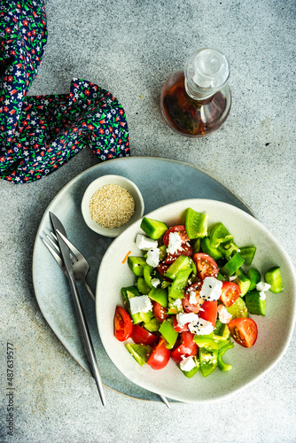 Overhead view of a bowl of fresh Greek salad with olive oil and sesame seeds