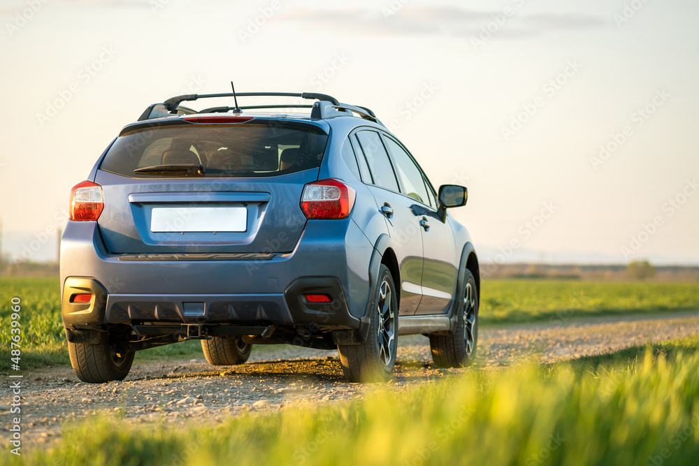 Landscape with blue off road car on gravel road. Traveling by auto, adventure in wildlife, expedition or extreme travel on a SUV automobile. Offroad 4x4 vehicle in field at sunrise.