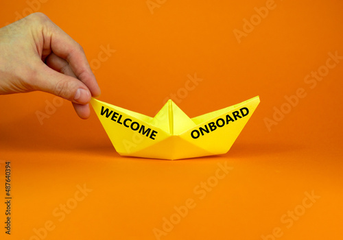 Welcome onboard and support symbol. Concept words Welcome onboard on yellow paper boat on a beautiful orange table orange background copy space. Businessman hand. Business and Welcome onboard concept.