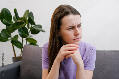 Tapet Pensive young woman 20s old years thinks of personal or relations problems, looks into distance feels thoughtful concerned sitting on sofa alone in living room
