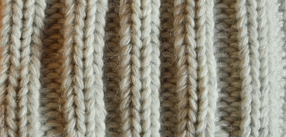 large knitting needles. texture with gray woolen threads. background for the design. the pattern is in braids.