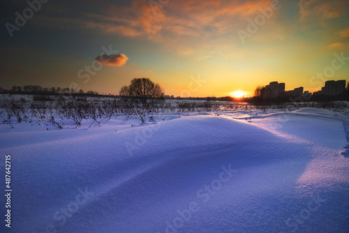 winter sunset with clouds over the fields of Kosinsky forest park and the city, Kosino-Ukhtomsky, Moscow, Russia, with snowdrift © Andrei