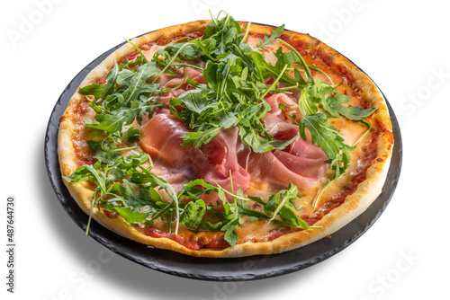 Pizza with parma ham, tomato sauce and rocket on black plate isolated on white, clipping path