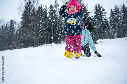 Mother and daughter having fun making and throwing snow balls.