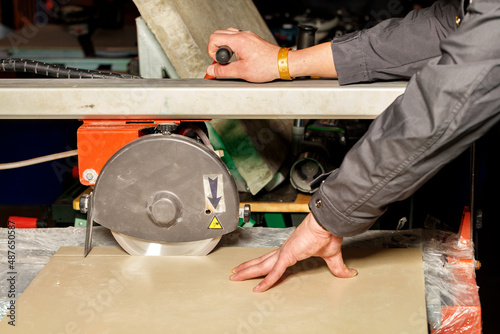 The master cuts a tile on an industrial machine with a diamond blade.