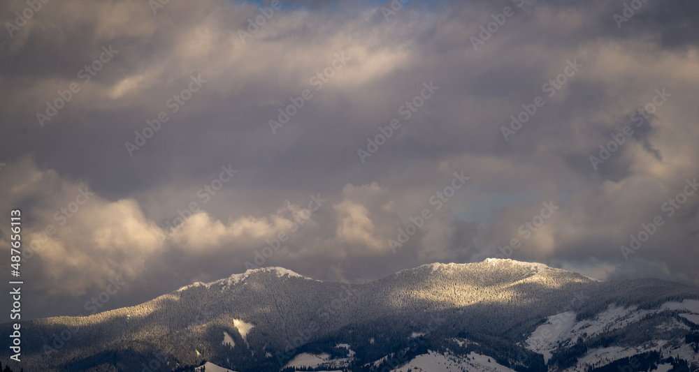 Amazing sunset. Winter forest. High mountains with snow white peaks.  Location place Carpathian, Vatra Dornei, Bucovina, Suceava, Romania, Europe.