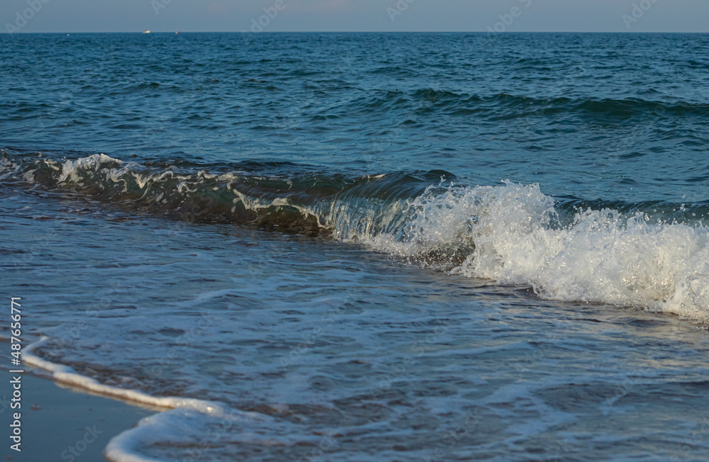 A large and strong storm wave of turquoise color with splashes of white foam runs and breaks on the shore A large and strong storm wave of turquoise color with splashes of white foam runs and breaks on the shore